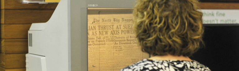 A woman using a microfilm viewer